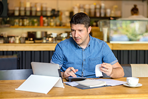 man sat at a table with a calculator and receipts