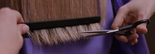 someone brushing through a head of hair and about to cut the ends off with a pair of scissors