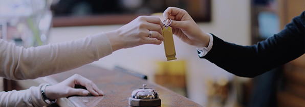 hotel receptionist handing a room key to a guest