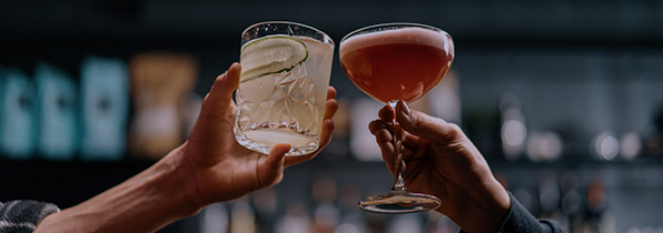 2 cocktail glasses being held in the air in a cheers position
