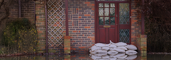 front of a house with a red front door with sand bags in front of the door to stop the flood getting in the house