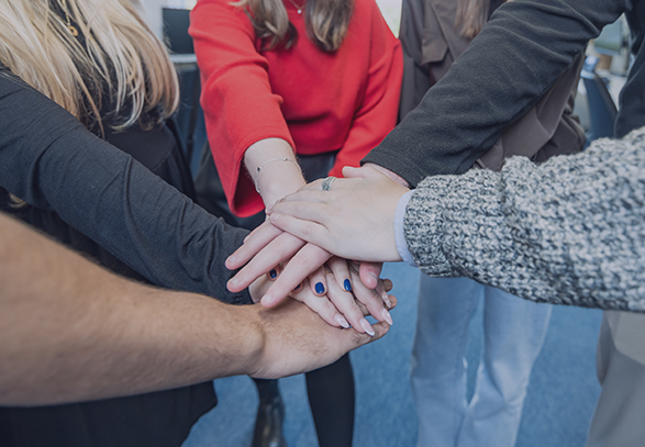 people stood in a circle with their hands in the middle